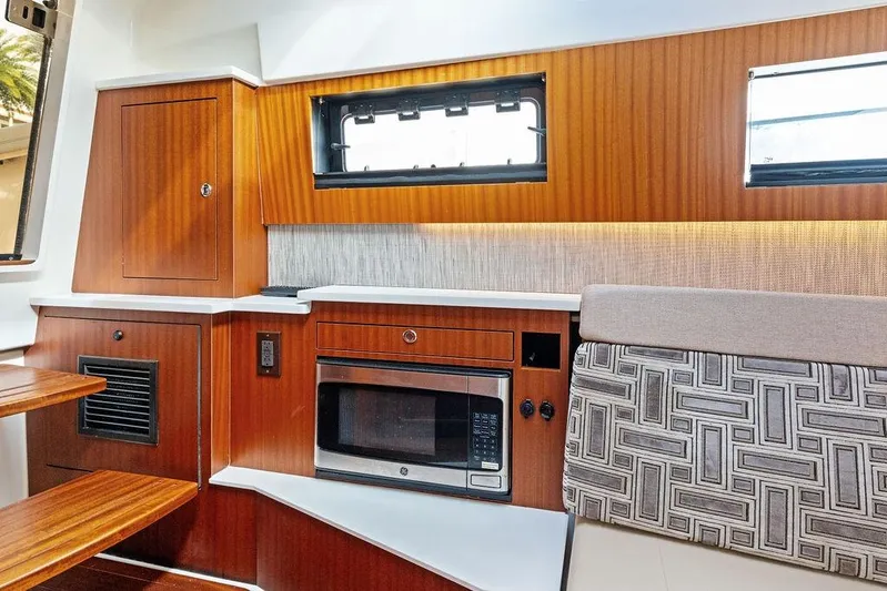 No Vacancy Yacht Photos Pics 2022 Pursuit S 428 Sport interior with wood cabinetry, microwave, and patterned seating.