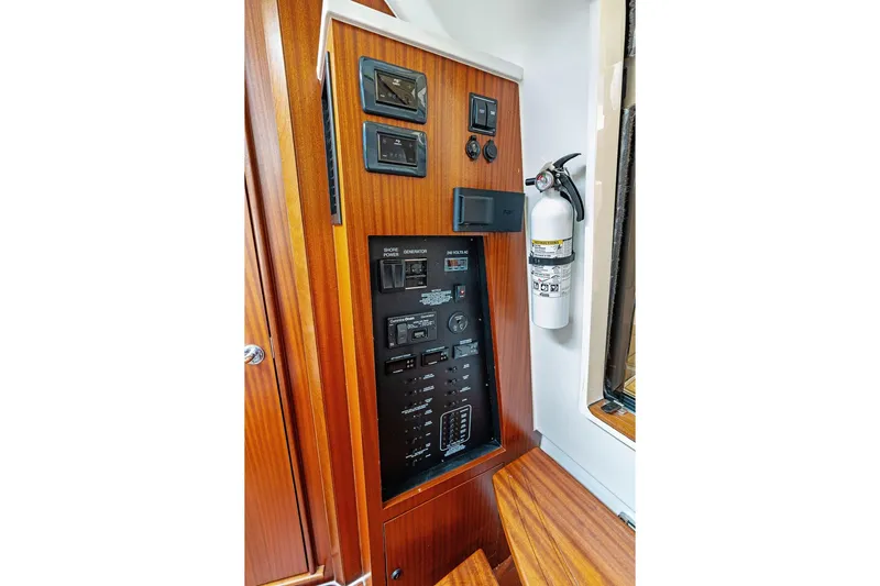 No Vacancy Yacht Photos Pics 2022 Pursuit S 428 Sport boat control panel with fire extinguisher, featuring wood finish.