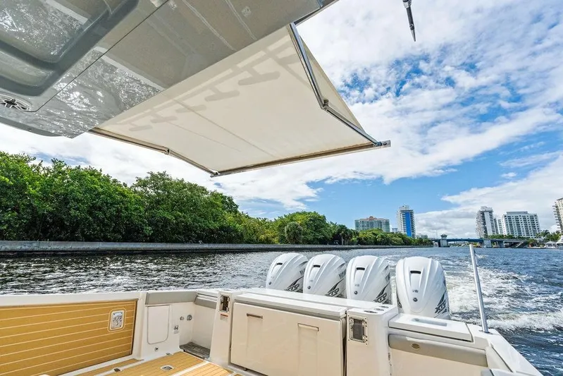 No Vacancy Yacht Photos Pics 2022 Pursuit S 428 Sport boat cruising on a sunny day with city skyline.