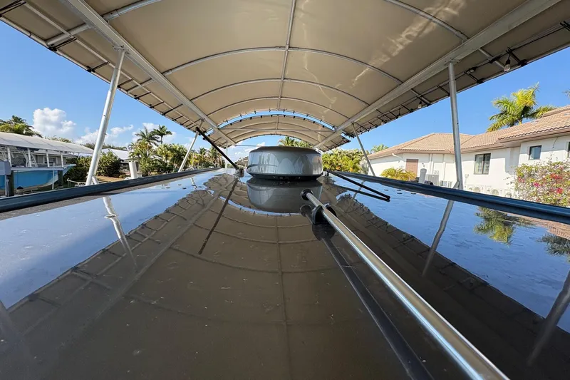  Yacht Photos Pics 2023 Nor-Tech 390 Sport Center Console under canopy, reflecting clear blue sky and tropical surroundings.