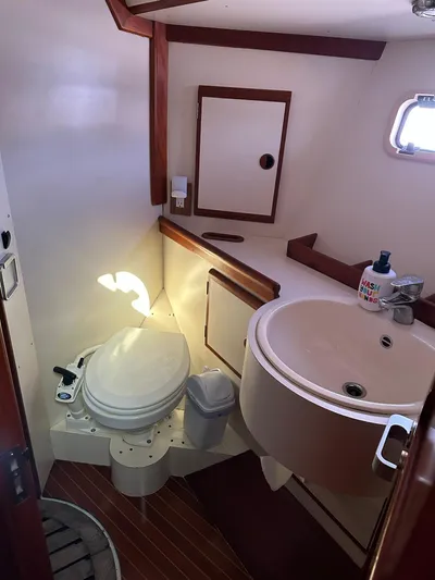 Sarama Yacht Photos Pics 1988 Custom Ancosta Dubois yacht bathroom with toilet, sink, and wooden accents.