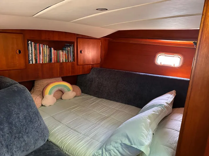 Sarama Yacht Photos Pics Cozy cabin interior of 1988 Custom Ancosta Dubois yacht with plush bedding and bookshelf.