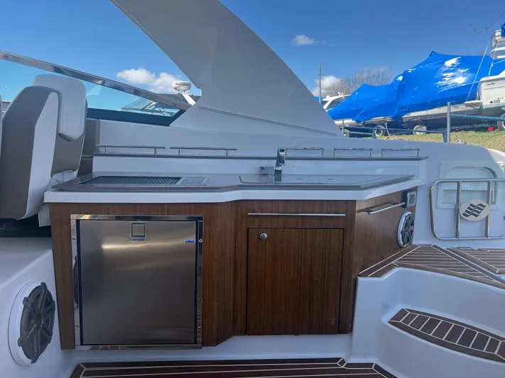  Yacht Photos Pics 2015 Four Winns H350 boat interior with kitchenette, featuring wood cabinetry and stainless steel appliances.