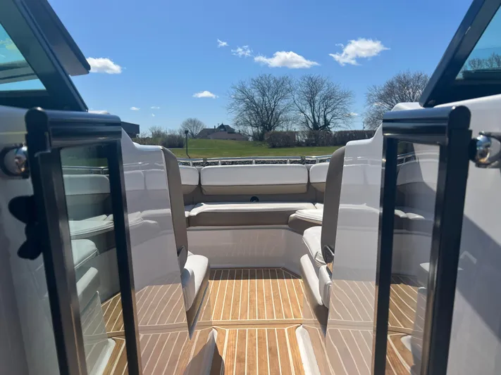  Yacht Photos Pics 2015 Four Winns H350 boat interior with wooden flooring and seating, under a clear blue sky.