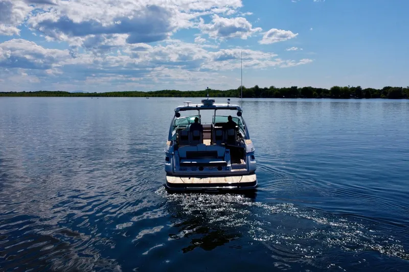  Yacht Photos Pics 2015 Four Winns H350 boat cruising on a calm lake under a partly cloudy sky.