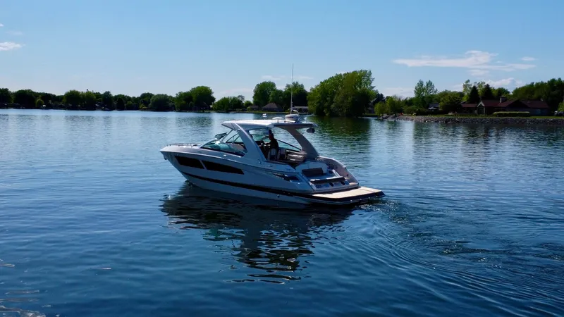  Yacht Photos Pics 2015 Four Winns H350 boat cruising on a calm lake under a clear blue sky.