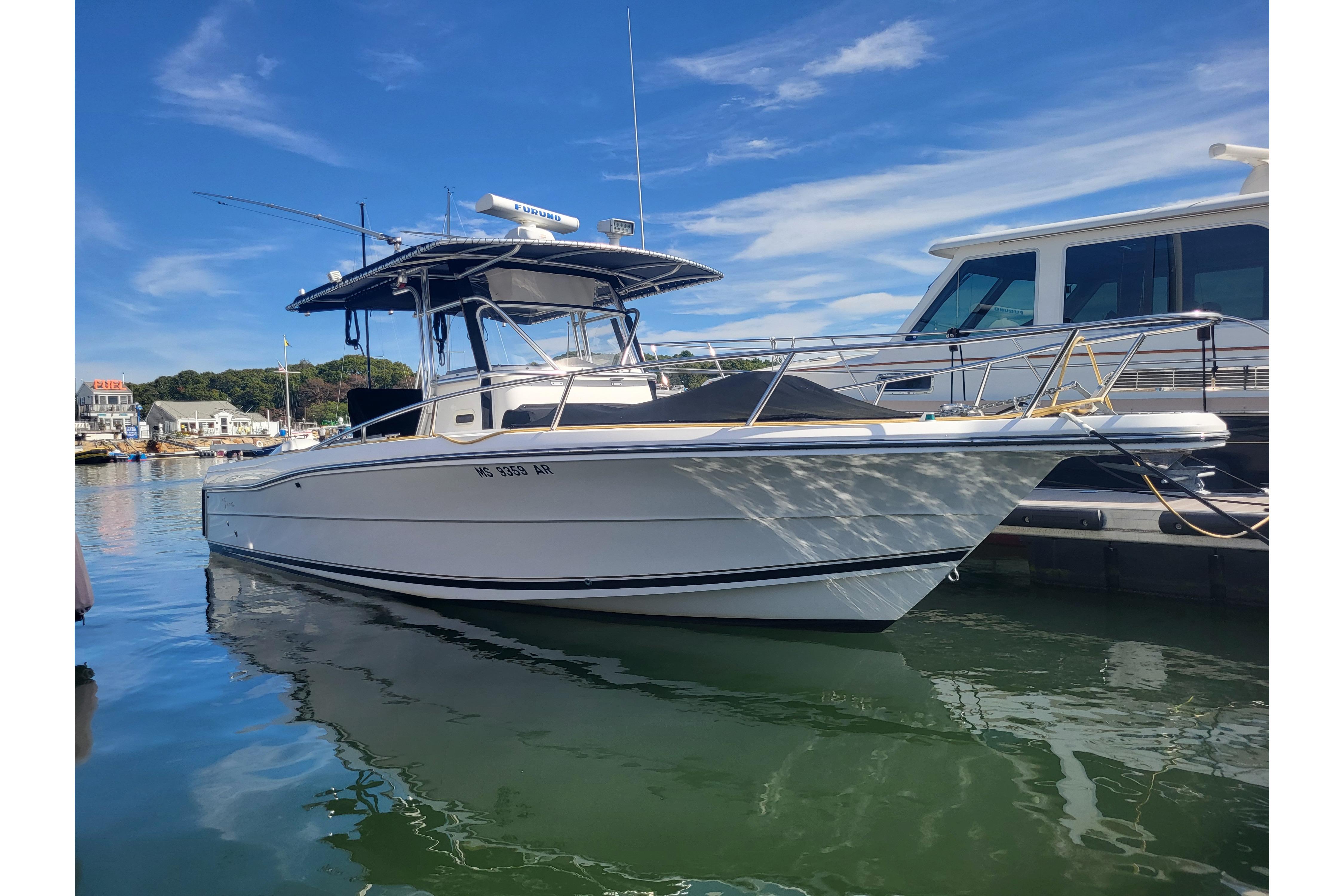 2005 Stamas 310 Tarpon boat docked in a marina under a clear blue sky.