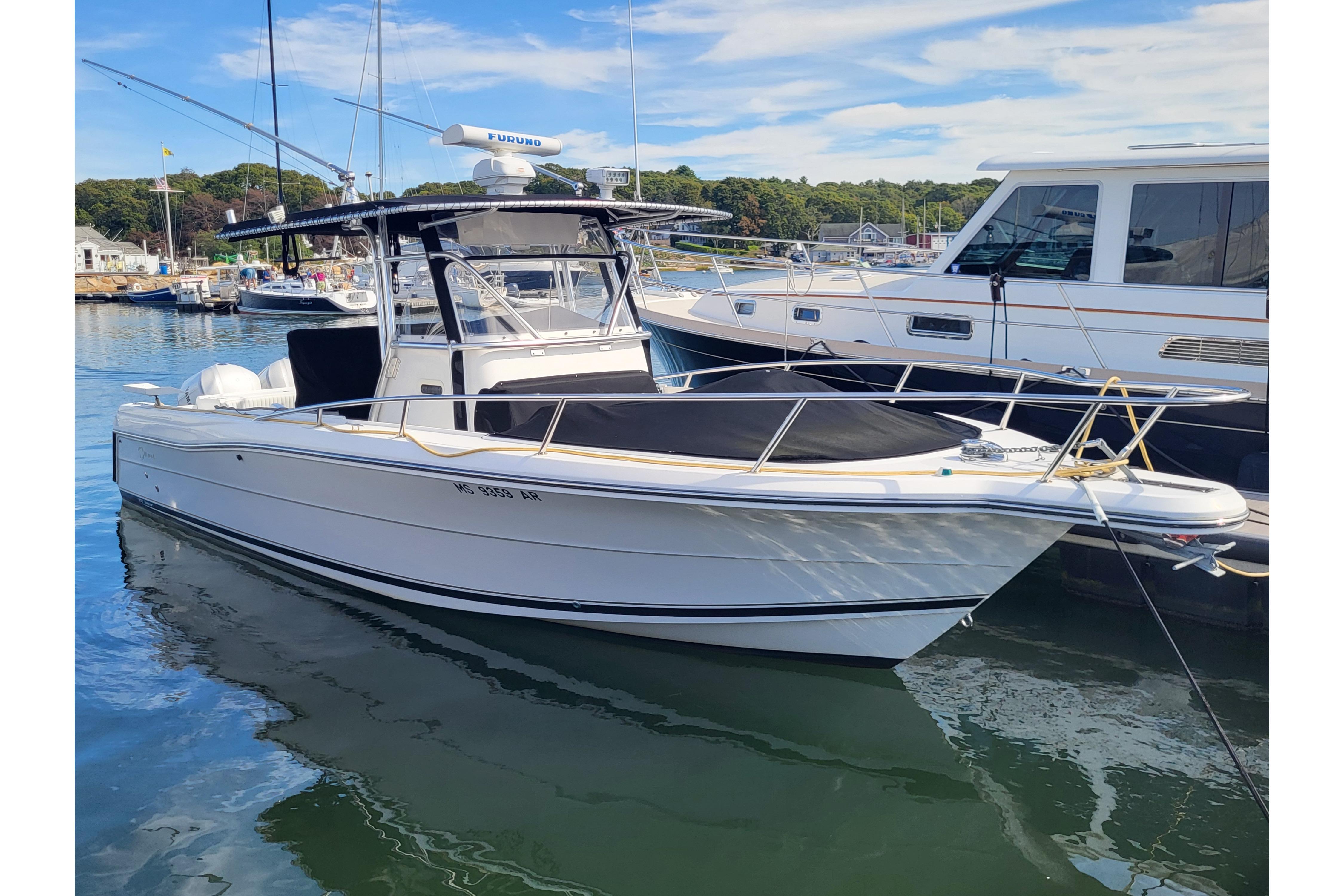 2005 Stamas 310 Tarpon boat docked in a marina, clear sky, calm water.