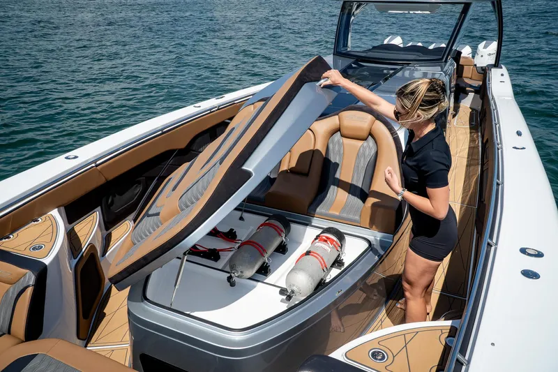  Yacht Photos Pics 2022 MTI V50 boat with open storage compartment, woman inspecting interior on water.