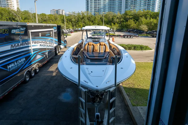  Yacht Photos Pics 2022 MTI V50 boat on trailer, parked near a building with cityscape background.