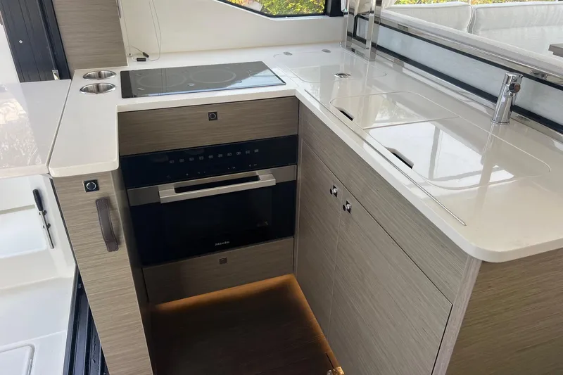 Yacht Photos Pics Modern kitchen area in 2024 Jeanneau NC 1295 Fly yacht with sleek appliances.