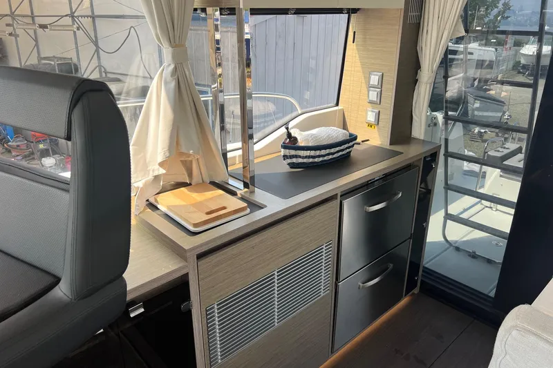  Yacht Photos Pics 2024 Jeanneau NC 1295 Fly interior kitchen with modern cabinetry and appliances.