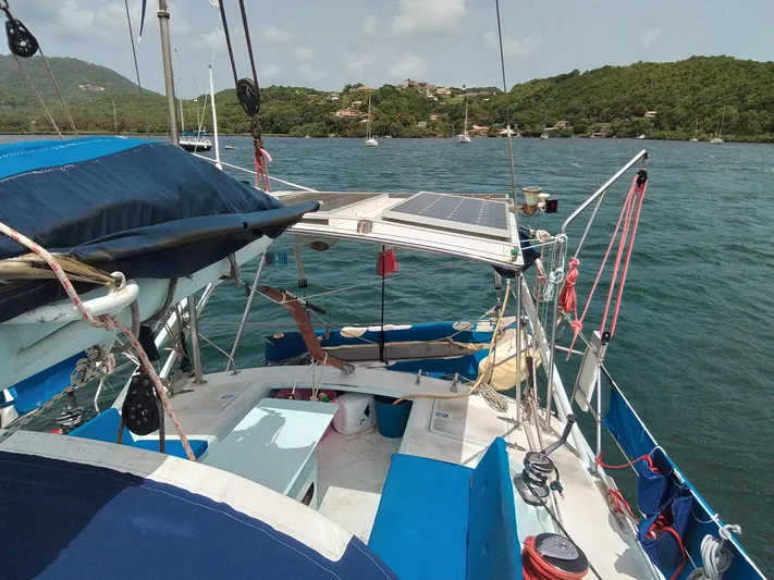 Atanahoue Yacht Photos Pics Sailboat "Paladin 60" on water, featuring solar panels, blue seating, and scenic coastal backdrop.