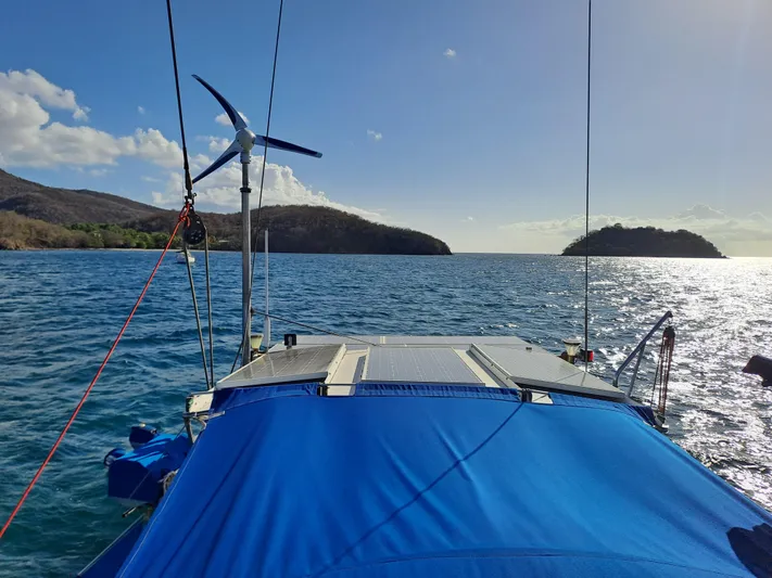 Atanahoue Yacht Photos Pics Sailboat with blue cover and wind turbine on a sunny day at sea.