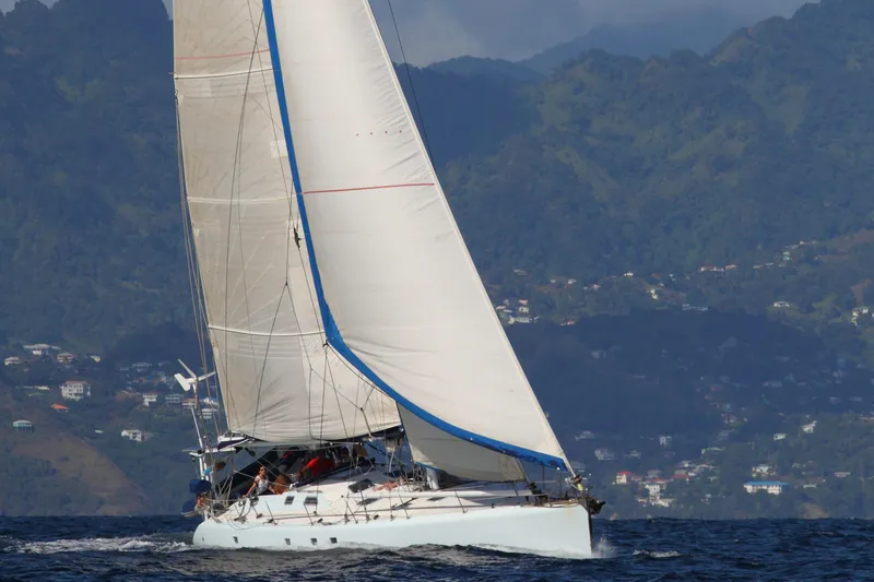 Atanahoue Yacht Photos Pics Sailing yacht "Paladin 60" gliding on ocean with lush hills in background.