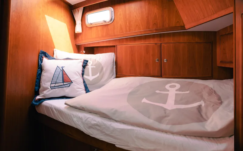  Yacht Photos Pics Cozy cabin interior of 2011 Privateer Trawler 50 with nautical-themed bedding and wooden finish.