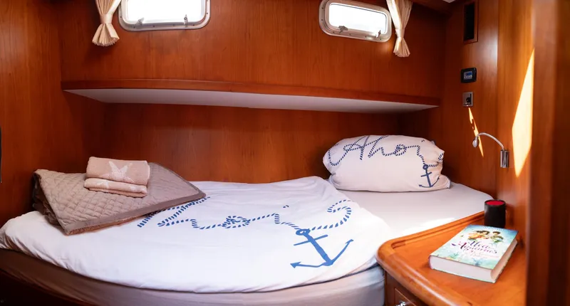  Yacht Photos Pics Cozy cabin interior of 2011 Privateer Trawler 50 with nautical-themed bedding and wooden finish.