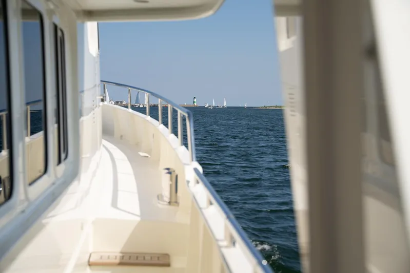  Yacht Photos Pics Privateer Trawler 50 yacht cruising on open water, 2011 model, with distant sailboats and lighthouse.