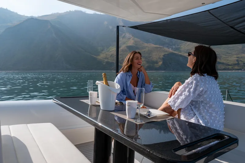  Yacht Photos Pics Two people enjoying a conversation on a 2025 Anvera 42 yacht, with scenic mountain views.
