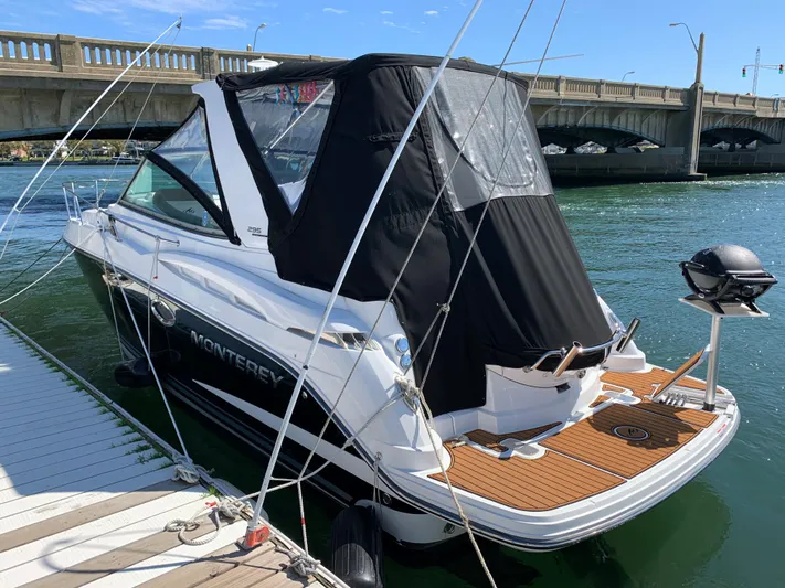  Yacht Photos Pics 2018 Monterey 295 Sport Yacht docked near a bridge, featuring sleek design and black canopy.