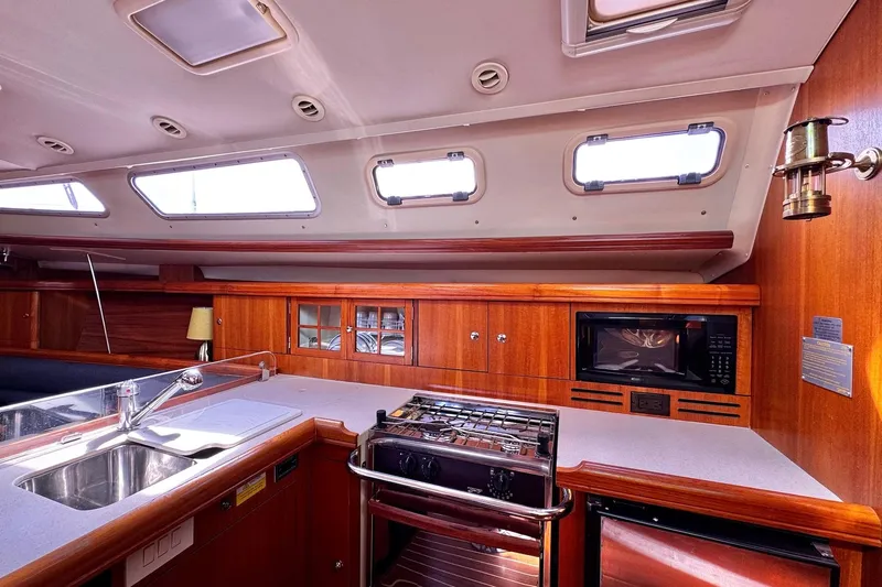  Yacht Photos Pics Interior of 2006 Hunter 38 sailboat kitchen with wood cabinetry and modern appliances.