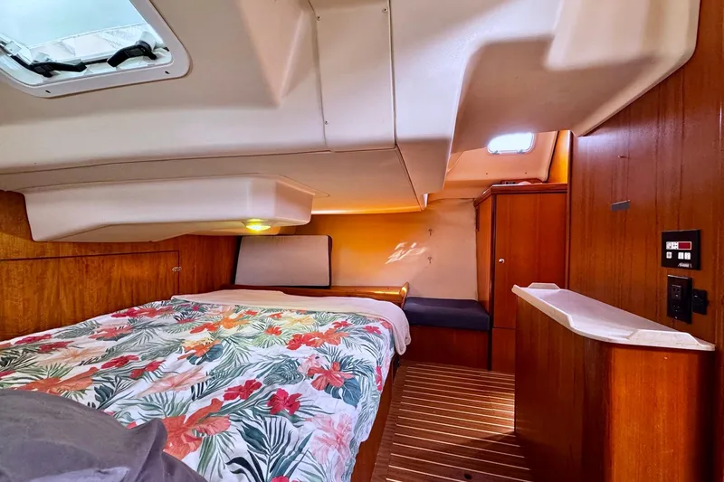  Yacht Photos Pics Interior cabin of 2006 Hunter 38 sailboat with floral bedding and wooden finishes.