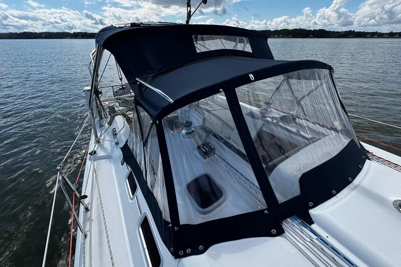  Yacht Photos Pics 2006 Hunter 38 sailboat with blue canopy on calm water under cloudy sky.