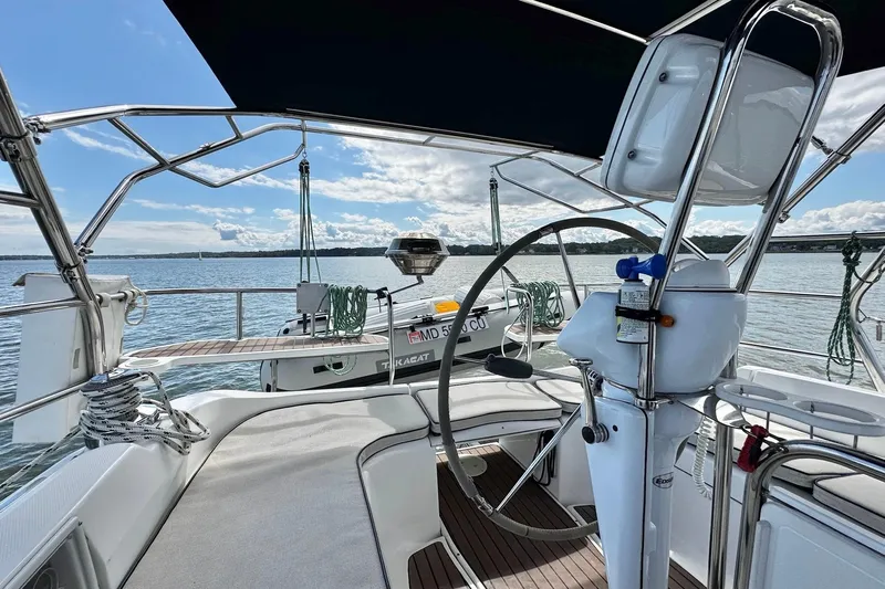  Yacht Photos Pics 2006 Hunter 38 sailboat cockpit with steering wheel, overlooking calm waters and clear sky.