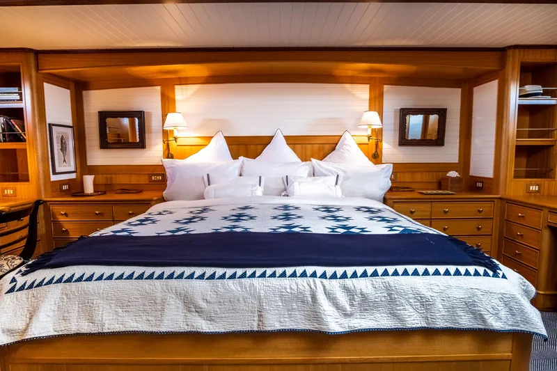 Fortuna Yacht Photos Pics Luxurious bedroom interior on 1999 Palmer Johnson motor yacht, featuring elegant woodwork and plush bedding.