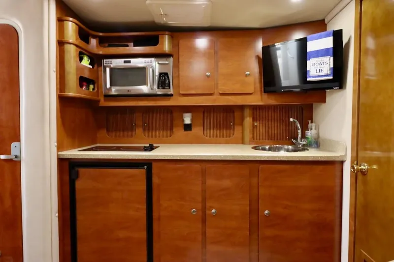 Pura Vida Yacht Photos Pics 2006 Rinker 360 Express Cruiser kitchen with wood cabinets, microwave, sink, and TV.