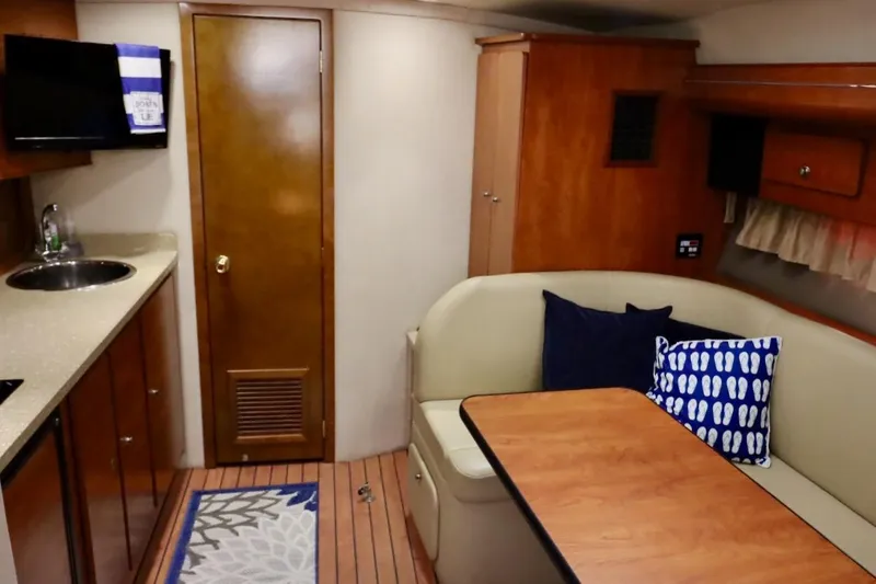 Pura Vida Yacht Photos Pics 2006 Rinker 360 Express Cruiser interior with kitchenette, seating area, and wooden cabinetry.