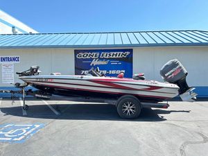 2013 Triton 19XS boat with Mercury engine parked outside a fishing store.