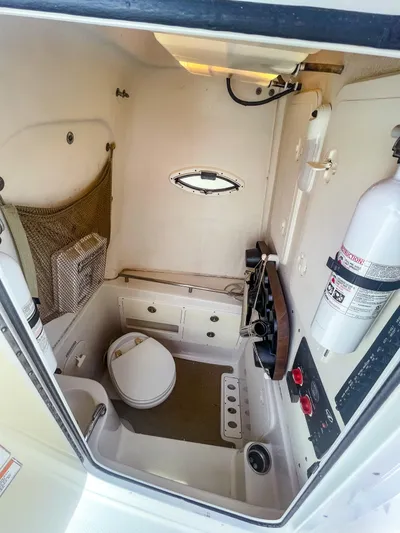 Yacht Photos Pics Interior of 2016 Sailfish 320CC boat bathroom with toilet, fire extinguisher, and storage compartments.