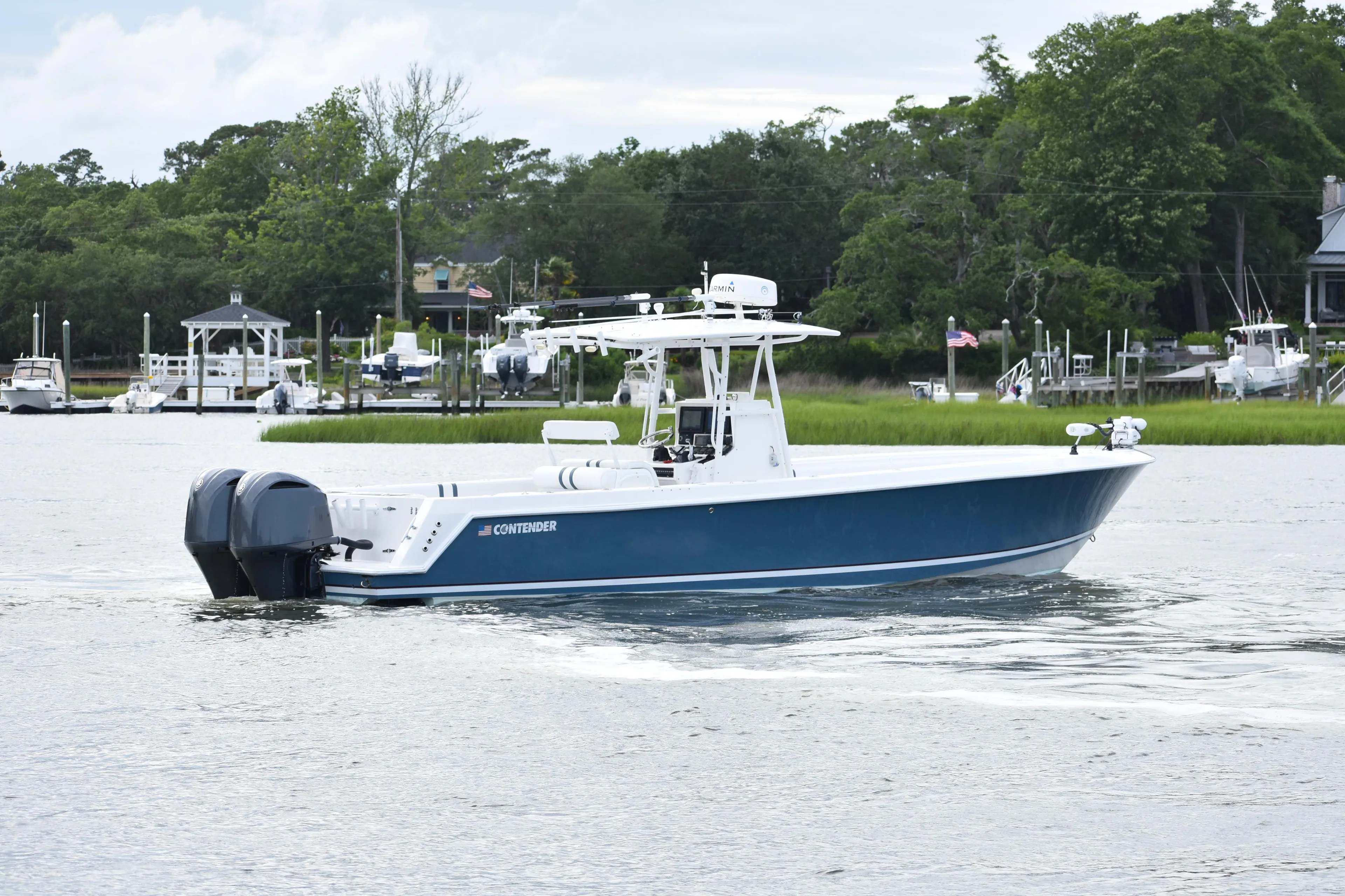2007 Contender 33 Tournament boat cruising on a calm river with lush greenery.
