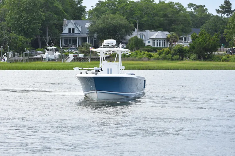  Yacht Photos Pics 2007 Contender 33 Tournament boat cruising on a calm river near waterfront homes.