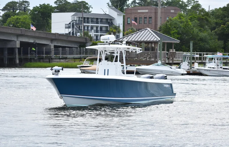 Yacht Photos Pics 2007 Contender 33 Tournament boat on a river near a dock and buildings.