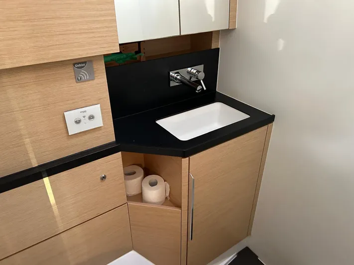  Yacht Photos Pics Modern bathroom sink in 2022 Hanse 510 yacht with wooden cabinetry.