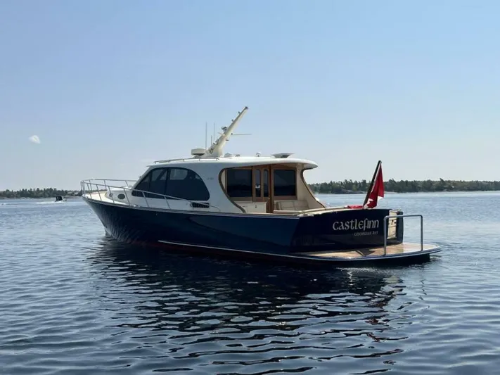 Castlefinn Yacht Photos Pics 2018 Palm Beach Motor Yachts PB55 on calm water, rear view with flag.