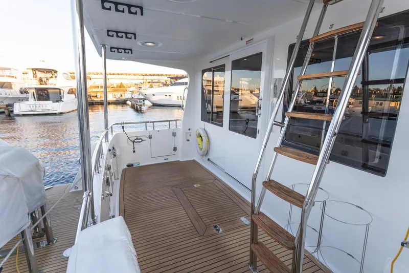 Boondoggle Yacht Photos Pics 2021 North Pacific 49 Pilothouse yacht deck with wooden flooring and ladder, docked at marina.