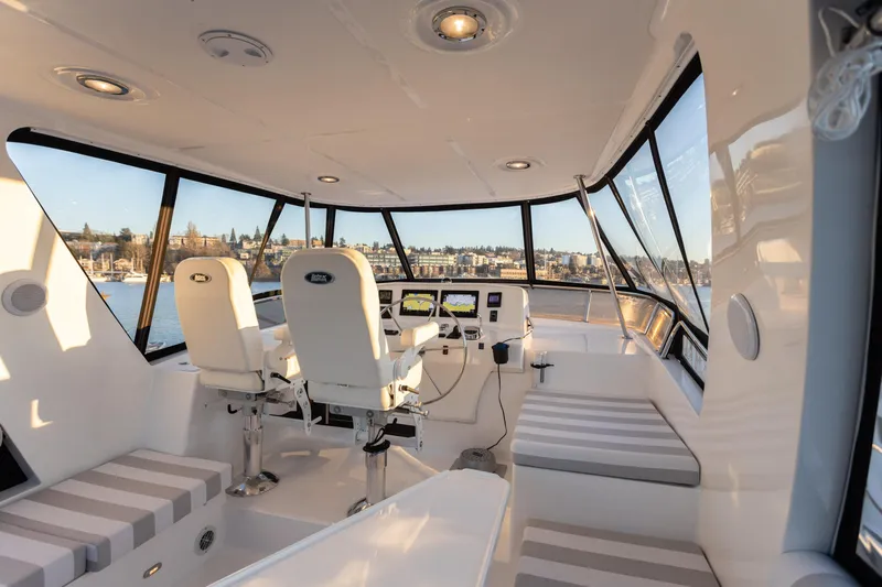 Boondoggle Yacht Photos Pics Pilothouse interior of 2021 North Pacific 49, featuring modern seating and panoramic windows.