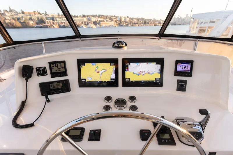 Boondoggle Yacht Photos Pics Pilothouse of 2021 North Pacific 49, featuring navigation screens and controls with scenic water view.