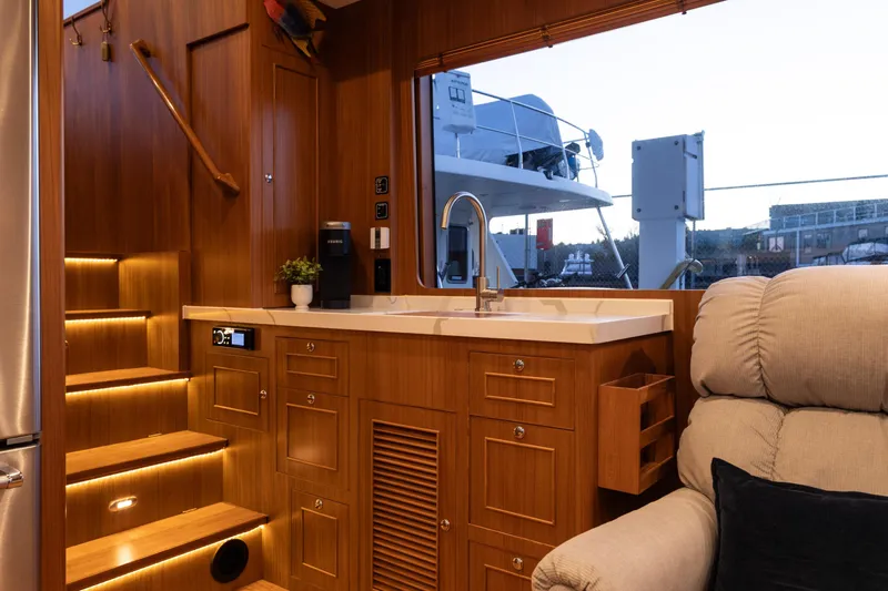 Boondoggle Yacht Photos Pics Luxurious interior of 2021 North Pacific 49 Pilothouse yacht with wooden cabinetry and modern amenities.
