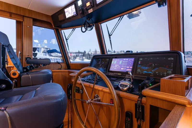 Boondoggle Yacht Photos Pics Pilothouse interior of 2021 North Pacific 49, featuring navigation screens and steering wheel.