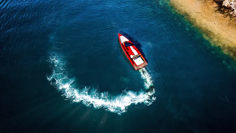 Corso Red Yacht Photos Pics Aerial view of 2021 Wally 48 boat making a circular wake in blue water.