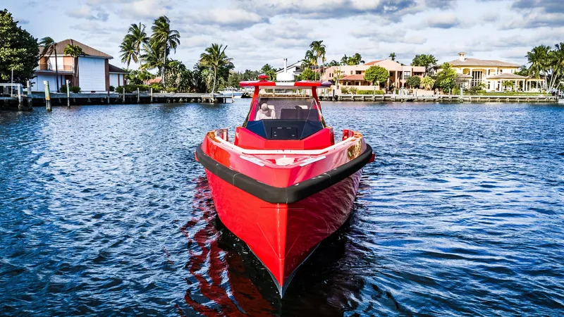 Corso Red Yacht Photos Pics Red 2021 Wally 48 boat on water, surrounded by palm trees and waterfront homes.