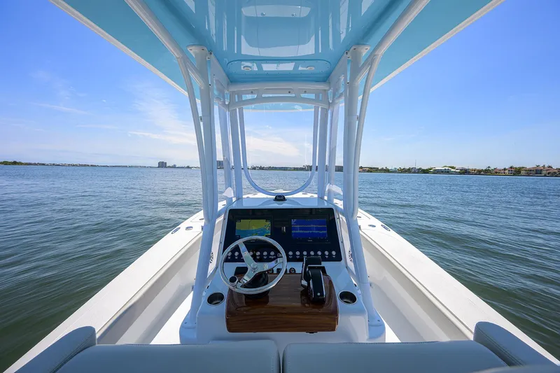  Yacht Photos Pics 2024 Conch 25 boat dashboard with steering wheel, on open water under clear blue sky.