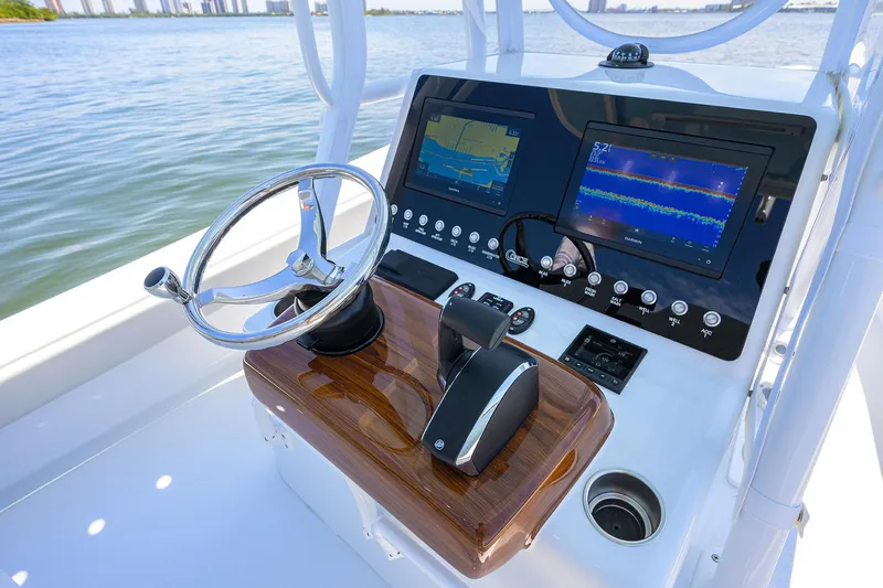  Yacht Photos Pics 2024 Conch 25 boat dashboard with navigation screens and steering wheel on calm water.