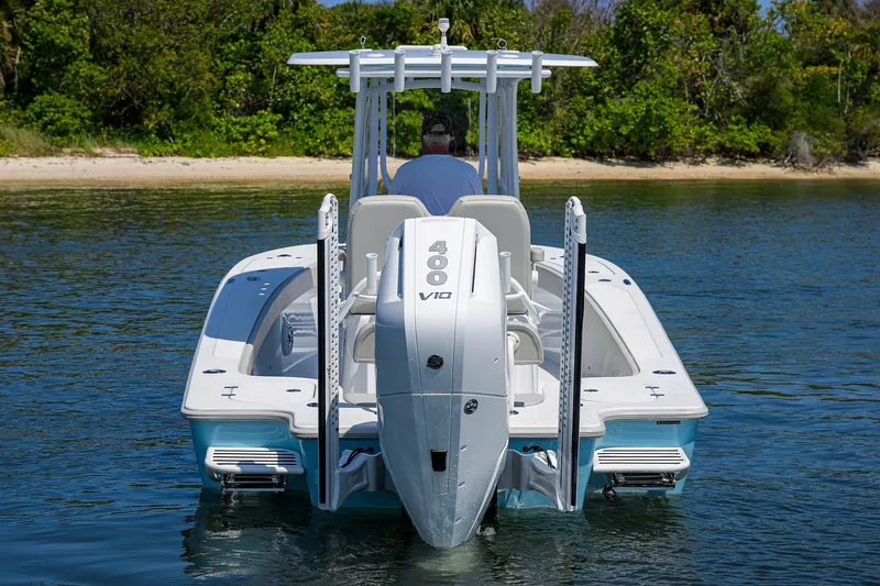  Yacht Photos Pics 2024 Conch 25 boat with powerful V10 engine, cruising on calm water near a lush shoreline.