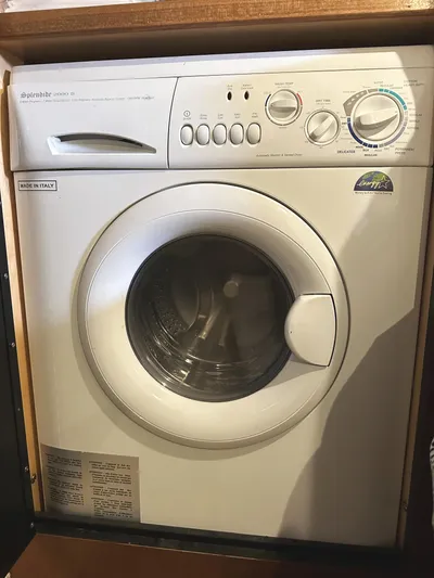 Rogue Yacht Photos Pics Front-loading washing machine in a wooden cabinet, featuring various control settings.