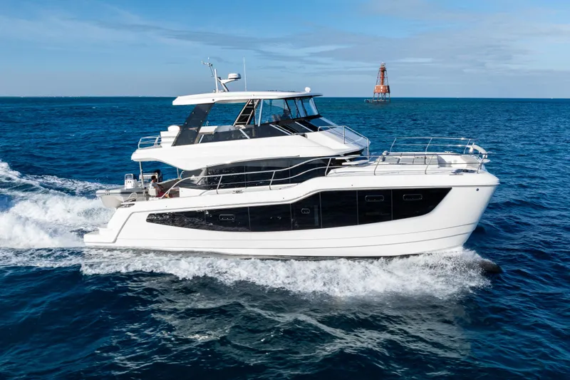  Yacht Photos Pics 2026 Aquila 50 Yacht cruising on open sea with lighthouse in background.